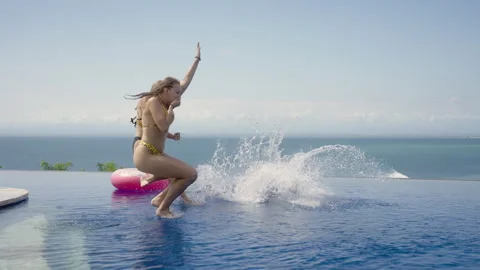 Friends run jump in ocean view infinity pool at luxury hotel resort villa Stock Footage 259158370