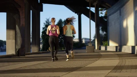 Friends Run Under Bridge Along Waterfront In City, Slow Motion Stock Footage 95961823