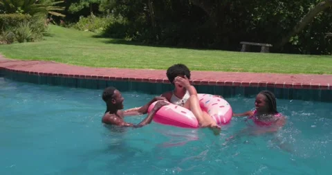 Friends running off backyard pool edge, splashing woman on pink donut float, Stock Footage 341241568