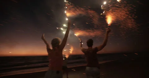 Friends running on a beach with fireworks Stock Footage