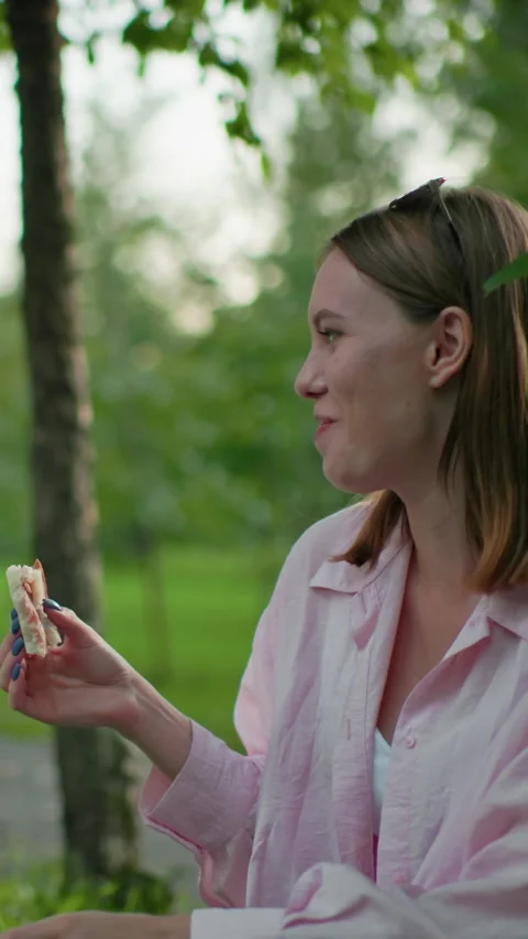 Friends Sharing Bread and Smiling Outdoors in Grassy Field with Trees Stock Footage 317581724