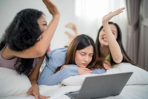Friends sharing a fun moment while watching something on a laptop in a cozy.. Stock Photos
