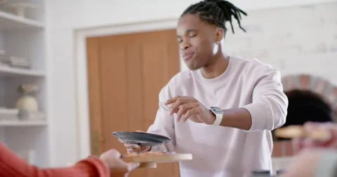 Friends sharing pizza at kitchen counter, red sweater extending board, African Stock Footage 346614604