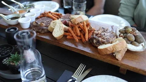 Friends sharing steak dinner platter Stock Footage 334489712