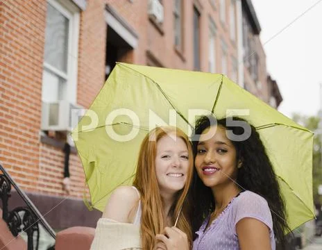 Friends sharing umbrella outdoors Stock Photos
