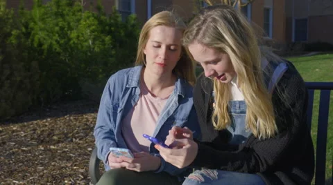 Friends Sit On Bench They Chat And Use Smartphones Video stock 62743513