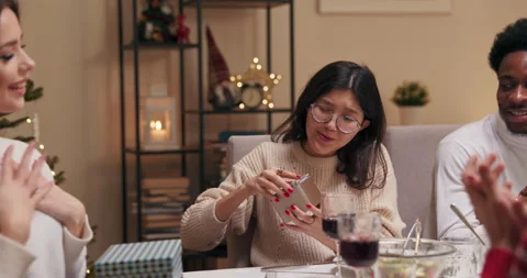 Friends sit at the festive table and give gifts. Brunette with long hair gives Stock Footage 218274876