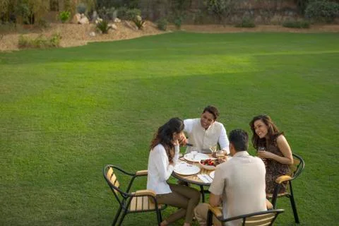 Friends sitting at dining table outside Stock Photos
