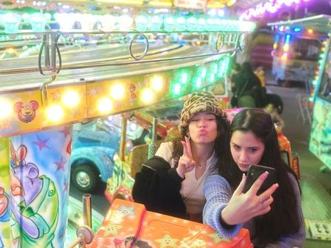 Friends sitting on a fairground ride while taking a selfie with funny Stock Photos