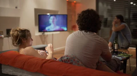 Friends sitting in the flat at night and watching television, steadycam shot Video stock 62961904