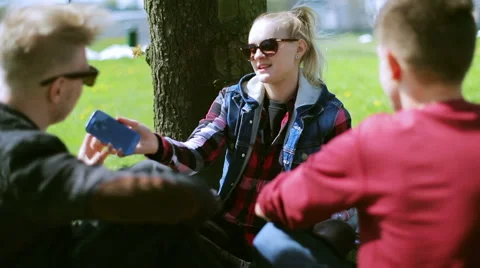 Friends sitting in the park and doing photos on smartphone Stock-Footage 49869399
