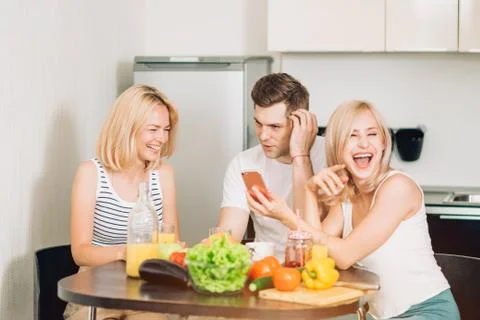 Friends sitting at table in kitchen Stock Photos