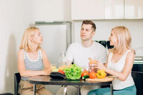 Friends sitting at table in kitchen Stock Photos