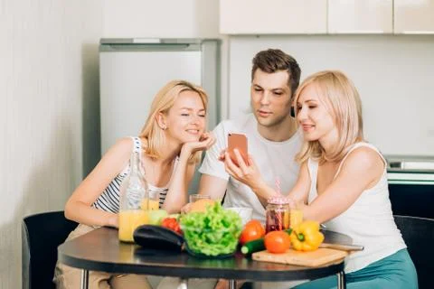 Friends sitting at table in kitchen Stock Photos