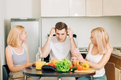 Friends sitting at table in kitchen Stock Photos