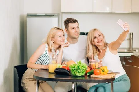 Friends sitting at table in kitchen Stock Photos