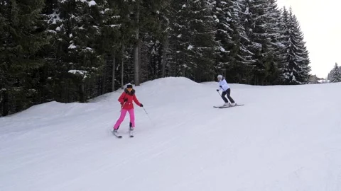Friends skiing down together on snow mountain piste across pine forest at winter Stock Footage 318838747