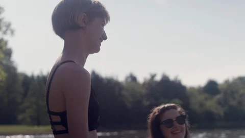 Friends smiling and laughing while cooling off in a forest lake on a summer day 스톡 동영상 116707273