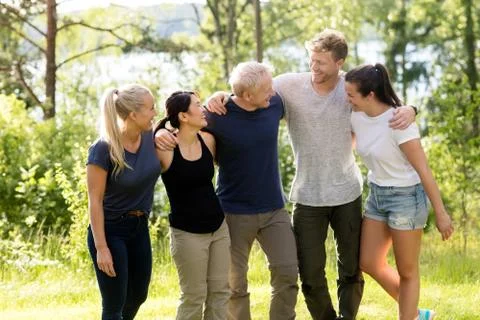 Friends Smiling While Standing Arms Around In Forest Stock Photos