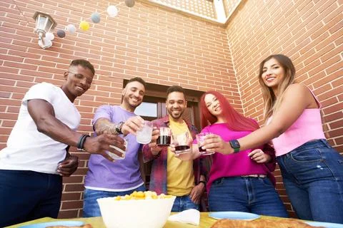 Friends smiling while toasting with drinks at an outdoor party. 스톡 사진