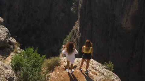 Friends stand on rock looking at gap between old mountains Stock Footage 141744015