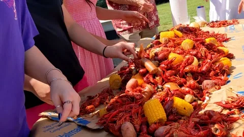 Friends standing around table in back yard eating crawfish fresh from the boiler Видео 276198421