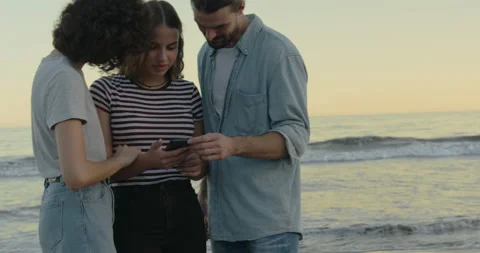 Friends standing with smartphone on beach Stock Footage 171267993