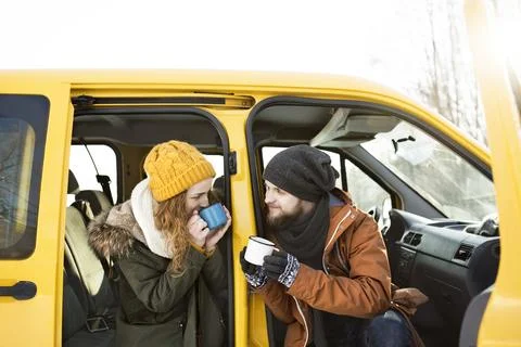 Friends taking break druing long ride to winter cabin, drinking hot tea in car Stock Photos