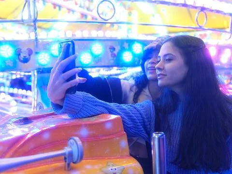 Friends taking a selfie while sitting inside a cart of a attraction in a fair Stock Photos