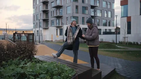 Friends talk and enjoy time outside at a playground in the city during the Stock Footage 343922904