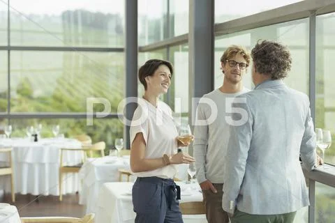 Friends talking and drinking wine in winery dining room Stock Photos