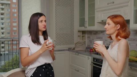 Friends talking and standing up while drinking coffee together in the kitchen. Stock Footage 295815074