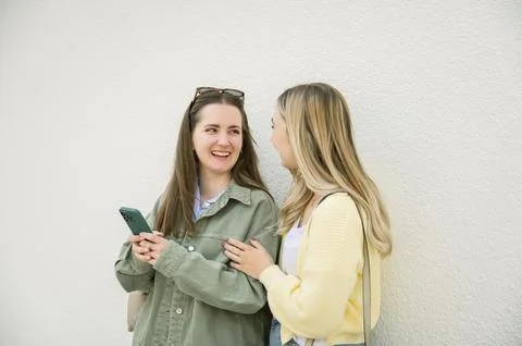 Friends talking while using phone standing outdoors Stock Photos