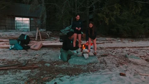 Friends tending campfire roasting marshmallows during twilight sunset aerial Stock Footage 334349461