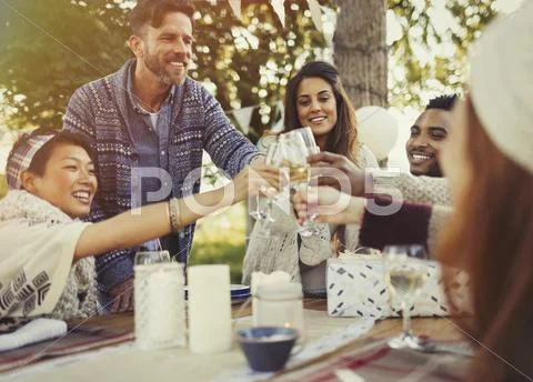 Friends toasting champagne glasses at birthday party patio table Stock Photos