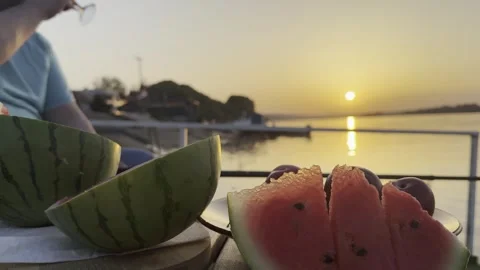 Friends Toasting Drinks with Watermelon at Sunset by the Sea 스톡 동영상 334570477