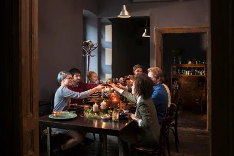 Friends toasting wine while having meal at table during Christmas Stock Photos