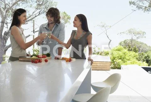 Friends Toasting Wineglasses At Kitchen Counter Stock Photos