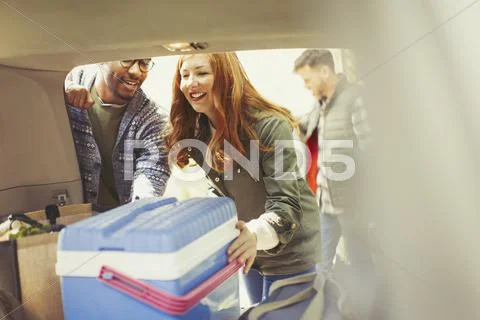 Friends unloading cooler from back of car Stock Photos