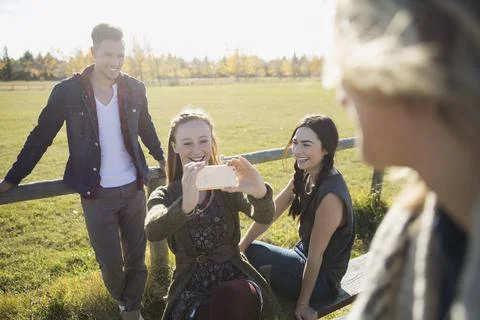 Friends using camera phone in sunny park Foto stock