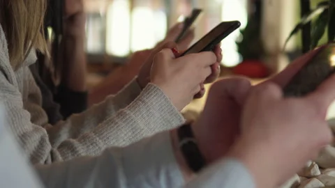 Friends using cell phones in a coffee shop, not talking to eachother and look 스톡 동영상 171838015