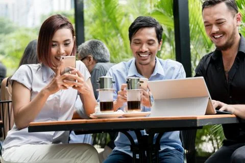 Friends using devices connected to the wireless internet of a modern coffee shop Stock Photos