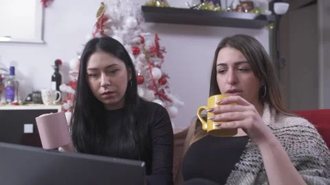 Friends using laptop and drinking coffee at home at Christmas Video stock 133374887