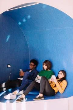 Friends using smart phones while sitting at library 스톡 사진