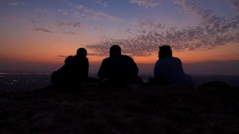 Friends with view of the sunset at the edge of the world in Saudi Arabia Stock Photos