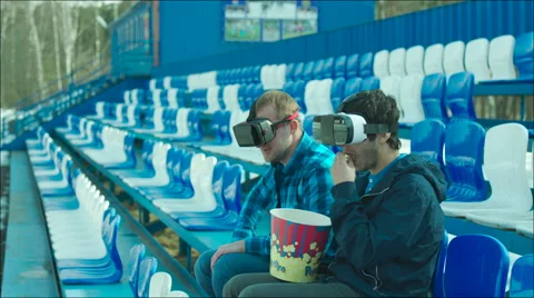 Friends in VR glasses rooting active on the stadium tribune Stock Footage 63844819