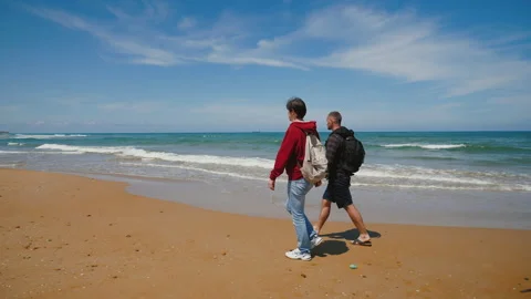 Friends walking on beach together. Two men talking and having fun near sea Stock Footage 218374953