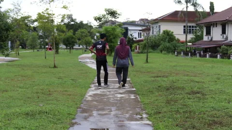 Friends walking in neighbourhood park Stock Footage