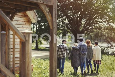 Friends walking outside lakeside cabin Stock Photos
