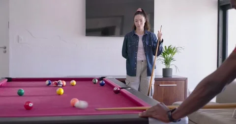Friends watching player lining up cue, taking shot for fun on pool table, her Stock Footage 337730191